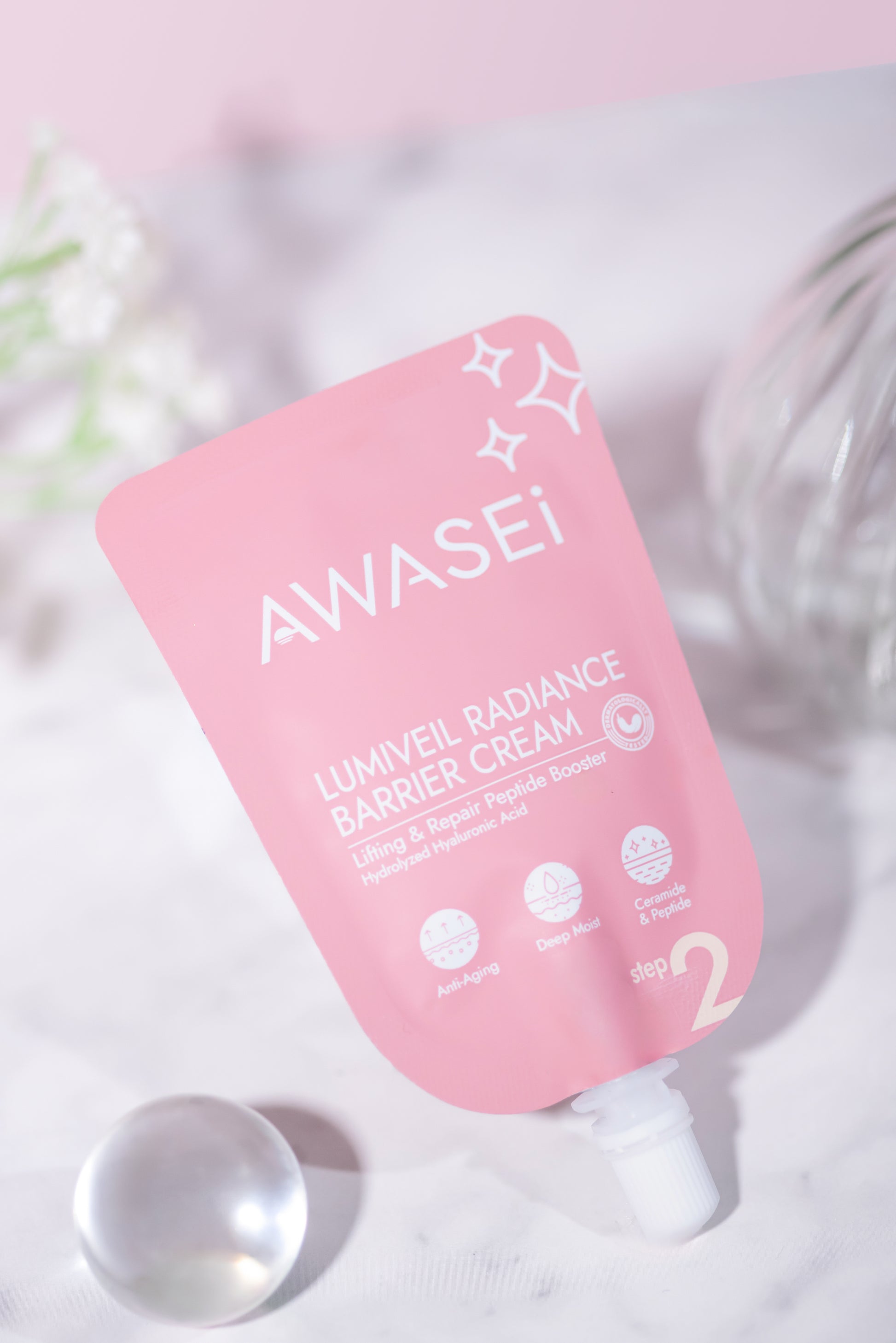 LUMIVEIL Radiance Barrier Cream ซองวางเอียงบนพื้นหินอ่อน ตกแต่งด้วยลูกแก้วใส